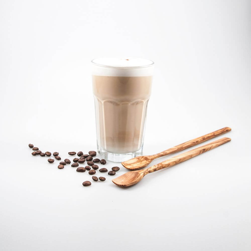 Latte Macchiato im Glas mit zwei Latte Macchiato Löffeln und Kaffeebohnen