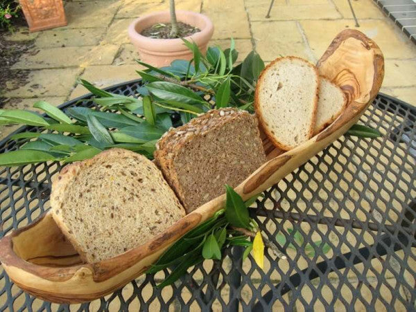 Brotschale aus Olivenholz in Naturform mit verschiedenen Brotscheiben