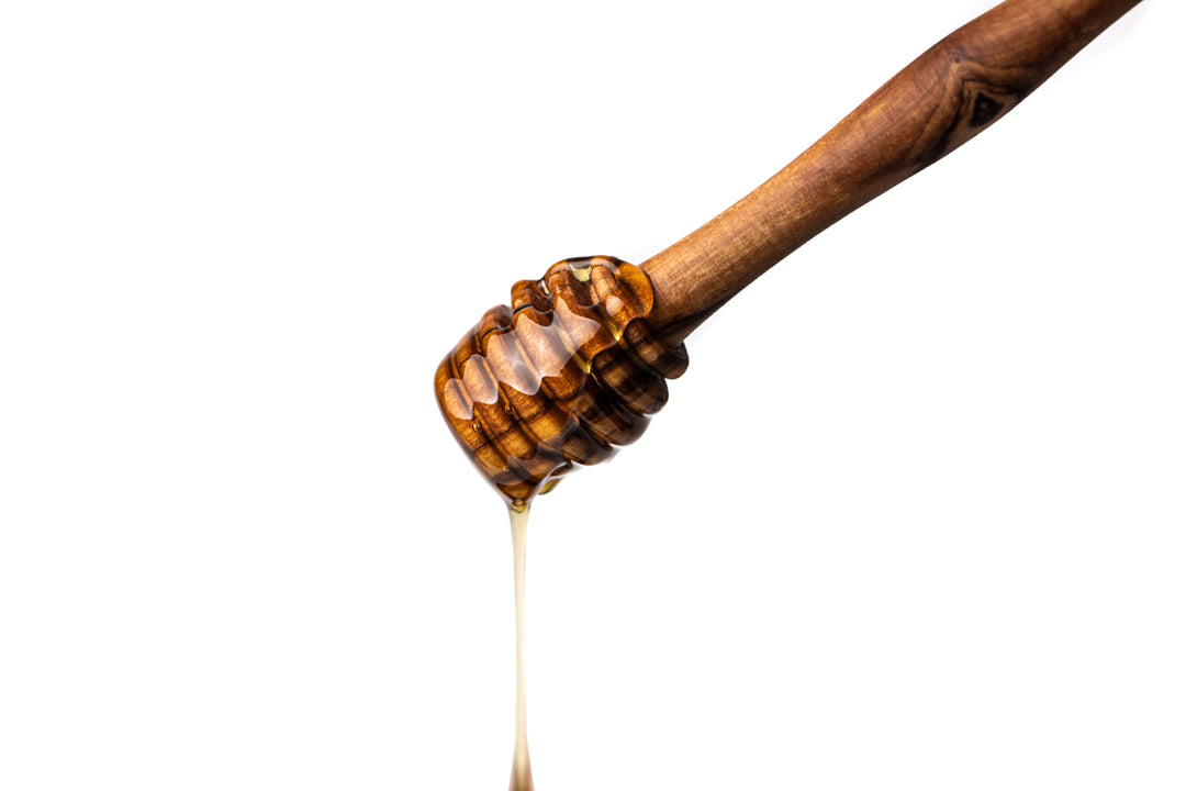 Honiglöffel aus Olivenholz mit tropfendem Honig