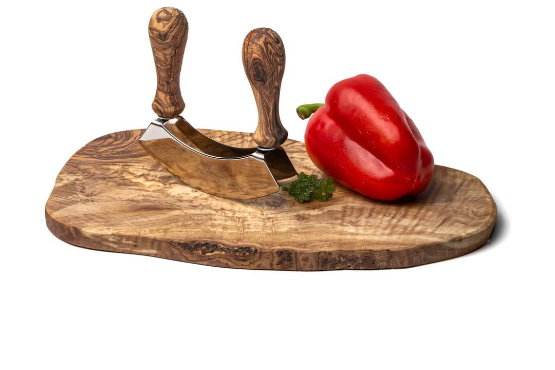 Schneidebrett aus Olivenholz im Naturschnitt mit Wiegemesser und Paprika